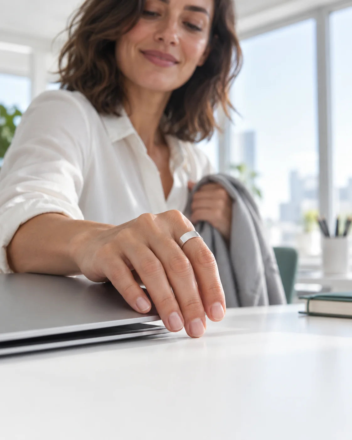 A woman closes her laptop at the end of the workday, the Vitality Ring on her index finger