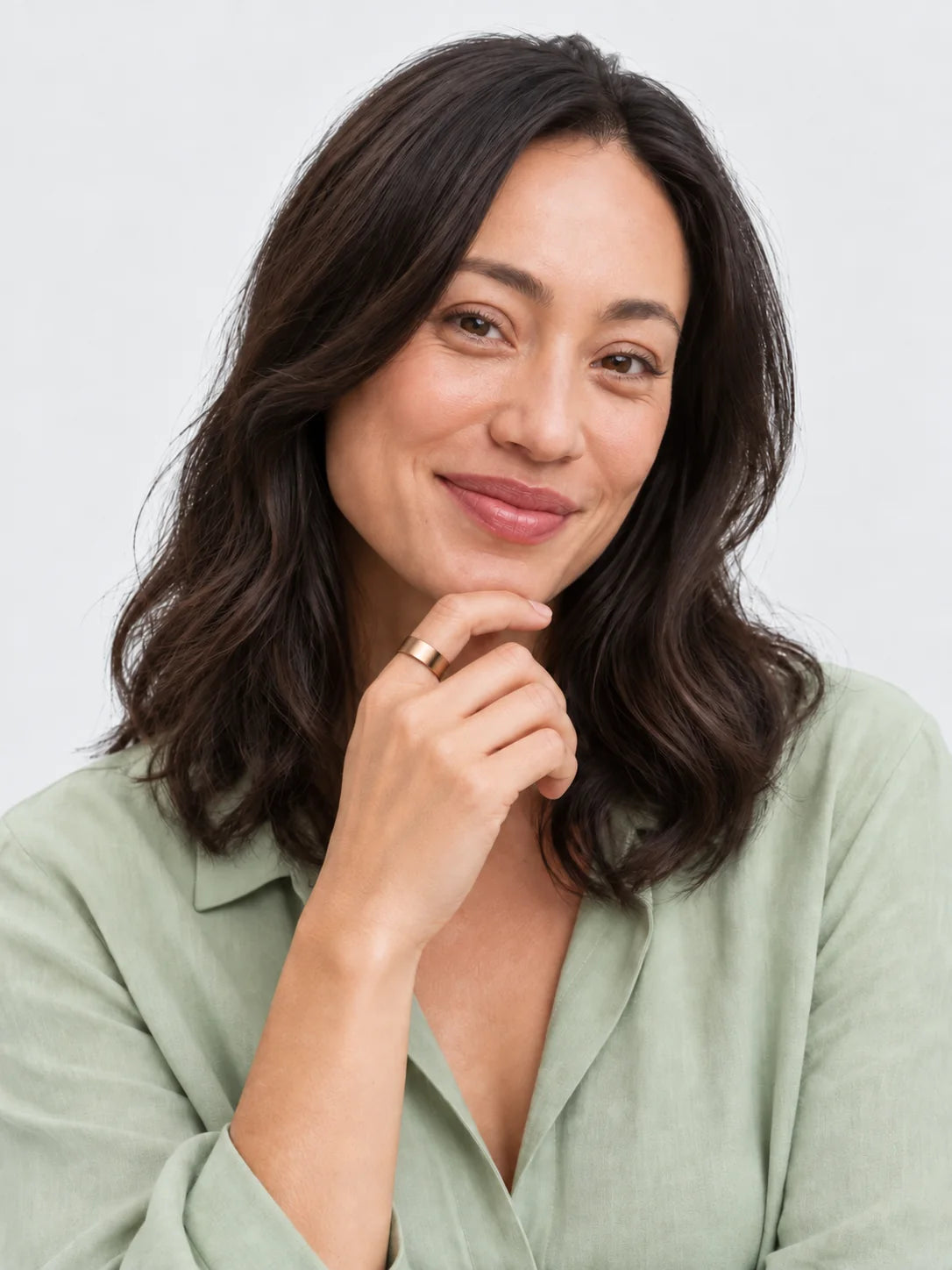 A woman in her late thirties in a sage blouse, hand at her chin, the Vitality Ring on her index finger